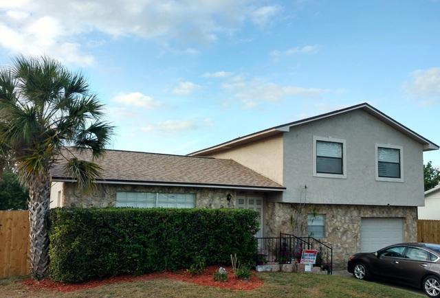 Tan home with brick & siding, with a new roof replacement in Orlando installed by the local roofing company; Alan's Roofing.