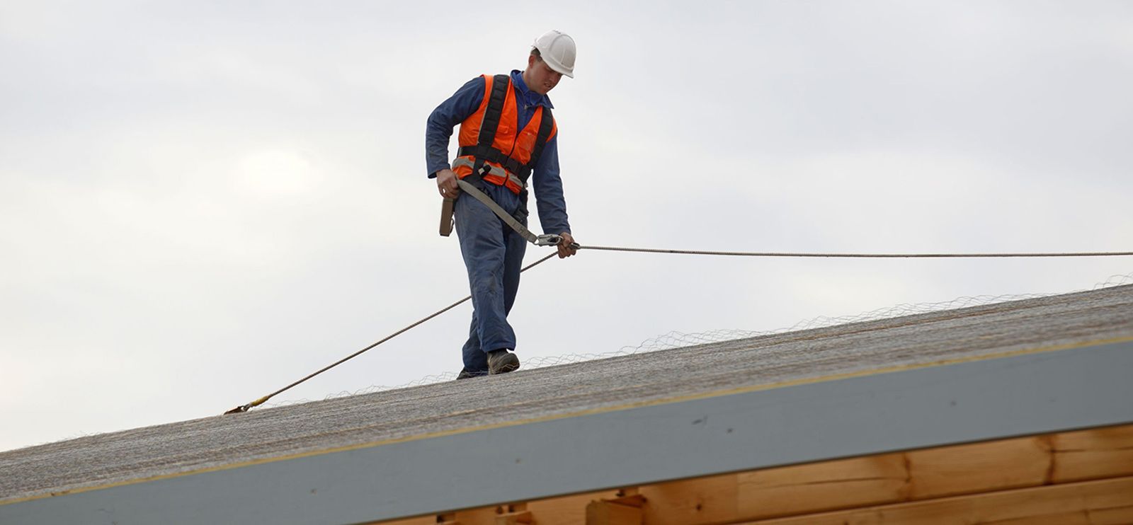 Roofer doing a roof inspection wearing a rope and safety harness on a residential home in Central Florida