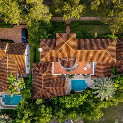 Aerial view of a luxury home with a tile roof, surrounded by lush greenery and a swimming pool in Port Charlotte 