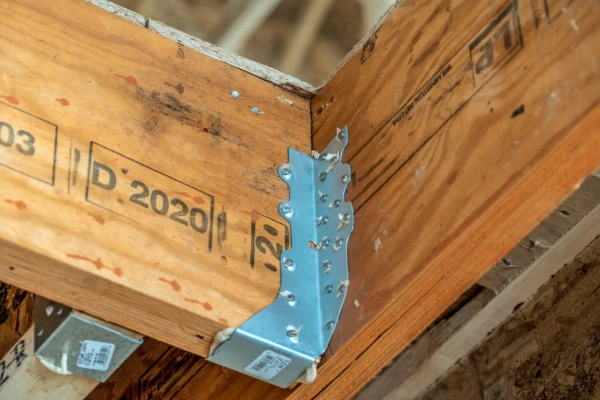 Close-up of hurricane straps connecting roof trusses to wall framing during a roof replacement project
