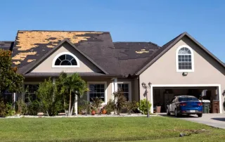 Aerial view of a Florida home with large sections of shingles missing after storm damage, exposing the wood decking underneath