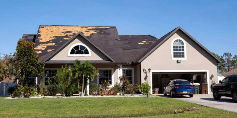Aerial view of a Florida home with large sections of shingles missing after storm damage, exposing the wood decking underneath